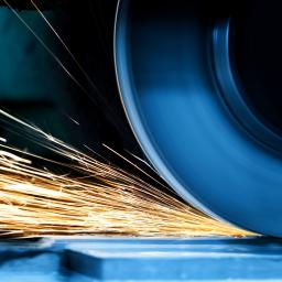 Close-up of a CNC grinding wheel removing material from a metal surface, producing bright sparks in a precision machining process.