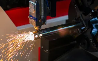 Pipe laser cutting in progress, showing a CNC laser cutting the end of a steel tube with sparks during metal tube cutting