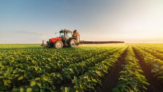 uk agriculture boom, tractor spraying soybean field.