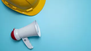PR analytics engineering concept megaphone and hard hat on blue background