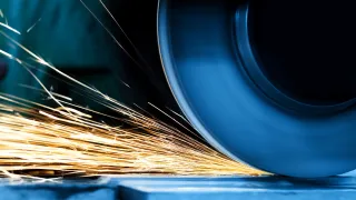 Close-up of a CNC grinding wheel removing material from a metal surface, producing bright sparks in a precision machining process.